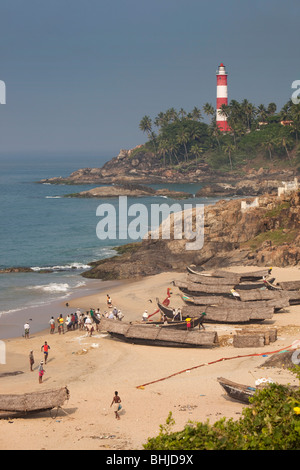 India, Kerala, Kovalam, Vizhinjam village fishing boats on beach in front of lighthouse Stock Photo