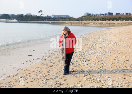 Plump woman walking on wintery beach Stock Photo
