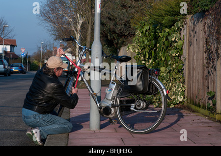 Bicycle thief takes wire cutters to steal chained up bike Stock Photo
