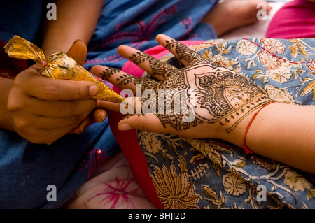A woman is applying a mahndi to another woman Stock Photo