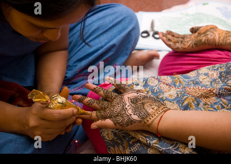 A woman is applying a mahndi to another woman Stock Photo
