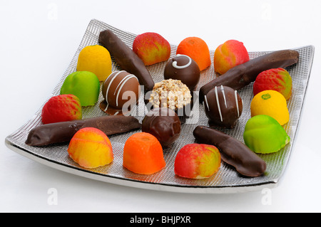 Chocolate truffles candied orange rind and marzipan candies on a silver plate on white Stock Photo