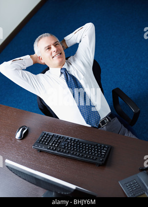 Mature business man leaning on chair with hands behind head, looking away and smiling. Copy space Stock Photo