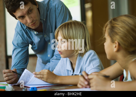 Teacher assisting students with their classwork assignments Stock Photo