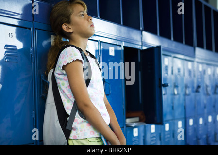 Female junior high student leaning against lockers contemplatively looking away Stock Photo