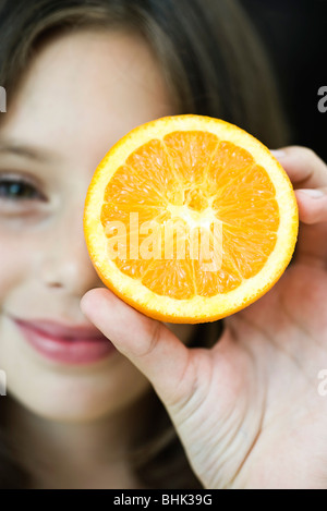 Girl holding up orange slice Stock Photo