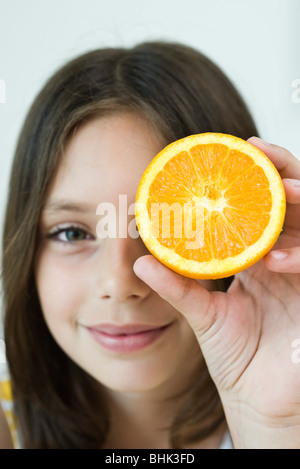 Girl holding up orange slice Stock Photo