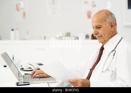 Doctor at desk busy with paperwork Stock Photo