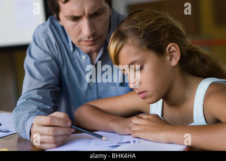 Teacher helping elementary school student in class Stock Photo