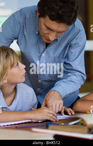 Teacher helping elementary school student in class Stock Photo
