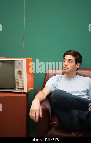 Man sitting in chair, looking away impatiently Stock Photo