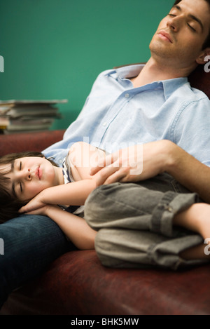 Father and son napping together on sofa Stock Photo