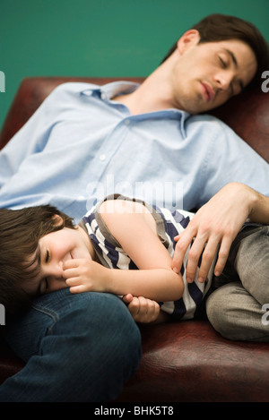 Father and son napping together on sofa Stock Photo