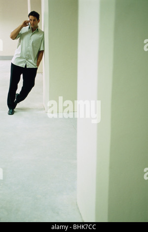 Man leaning in doorway, talking on cell phone Stock Photo