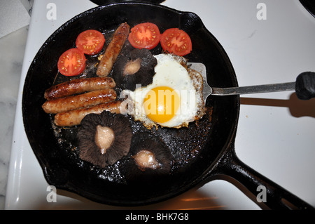 Full English breakfast in a cast-iron frying pan on a wooden light