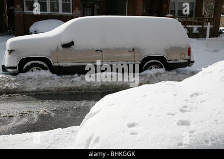 snow covers and surrounds a car and truck parked on a street in winter ...