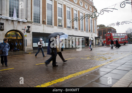 Pedestrians cross the road in the rain, Kingston, Surrey, England. Stock Photo