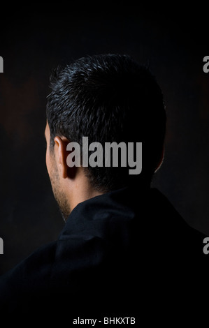 Rear view portrait of a young man standing in the dark