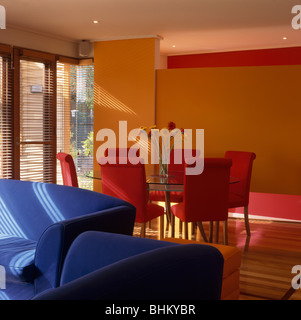 Bright blue sofas and modern orange dining room with red upholstered chairs Stock Photo