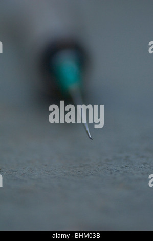 Dirty injection needle on the ground Stock Photo