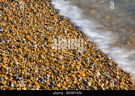 Hastings, East Sussex, England. Sunlit pebbles washed by the incoming tide. Stock Photo