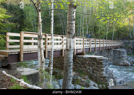 A hiker on a footbridge in the White Mountains, NH.  At the end of this bridge hikers enter into the Pemigewasset Wilderness Stock Photo