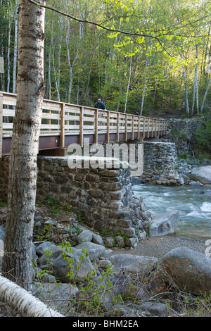 A hiker on a footbridge in the White Mountains, NH.  At the end of this bridge hikers enter into the Pemigewasset Wilderness Stock Photo