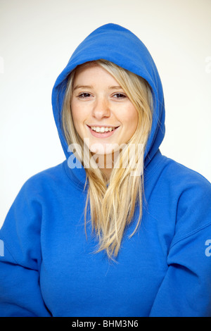 Blonde teenage girl wearing a hoodie sitting against a wall, Essex UK ...