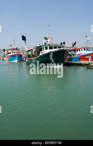 Fishing boats in the Royal Harbour at Ramsgate, Kent, United Kingdom. The large crates are used to store the nets Stock Photo