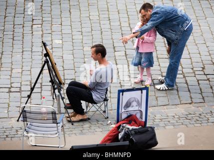 Father with daughter contemplating the work of a street artist painting in a painting easel, Dresden, Germany Stock Photo