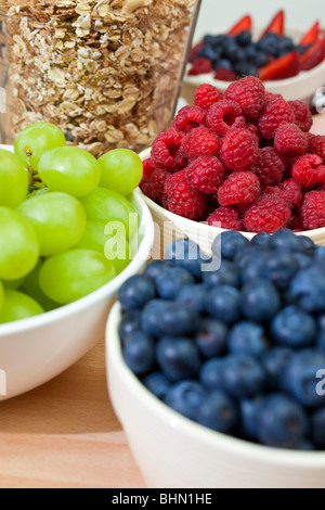 Bowls of healthy breakfast blueberries, raspberries, grapes, strawberries and granola or muesli Stock Photo