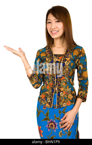 Malaysian girl wearing batik kebaya holding hand showing something Stock Photo
