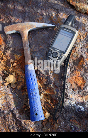 Mining exploration; geologists rock hammer and GPS unit on mineral rich rock background, H Stock Photo