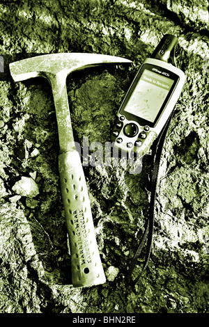 Mining exploration; geologists rock hammer and GPS unit on mineral rich rock background Stock Photo