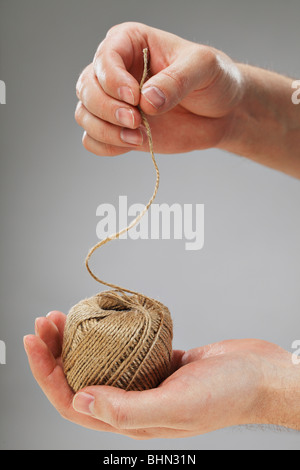 Hand holding a roll of natural fibre string Stock Photo