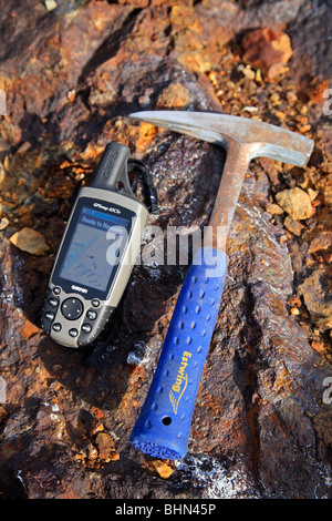 Mining exploration;  geologists rock hammer and GPS unit on mineral rich rock background Stock Photo