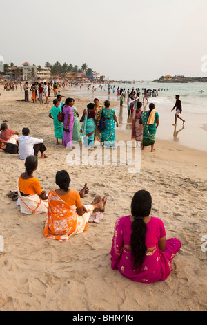 India, Kerala, Kovalam, Hawah (Eve) Beach, Indian tourists sat on beach Stock Photo