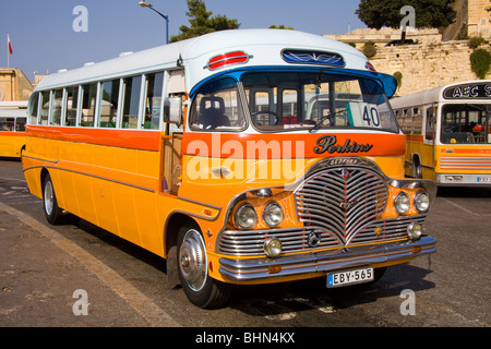 Orange+yellow public transport bus, parked at the bus terminus in Valletta on the island of Malta Stock Photo