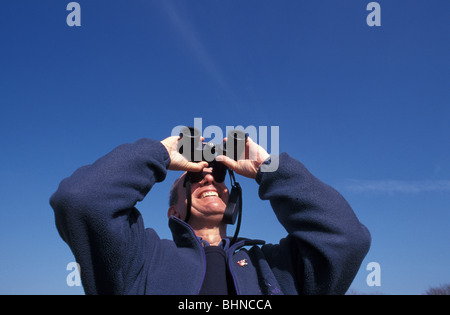 Birwatcher using binoculars on a bright sunny day Stock Photo