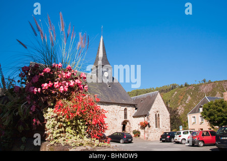 Church and flower garden with cars parked outside in Place de l'eglise, St Leonard des Bois, Pays de La Loire, France Stock Photo