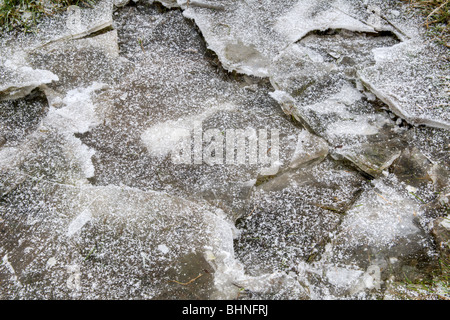 Puddle with broken thick frozen ice Stock Photo