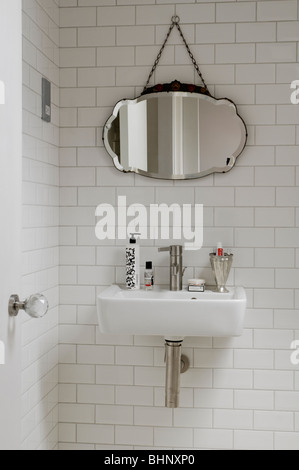 Washbasin and antique mirror in modern running-bond tiled bathroom Stock Photo