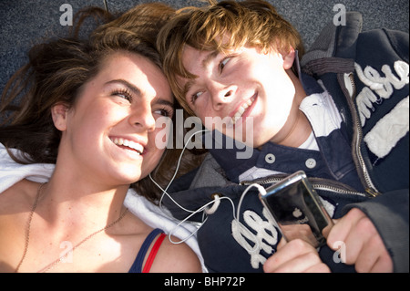 Teenage couple lay heads close listening to iPod . Model released Stock Photo