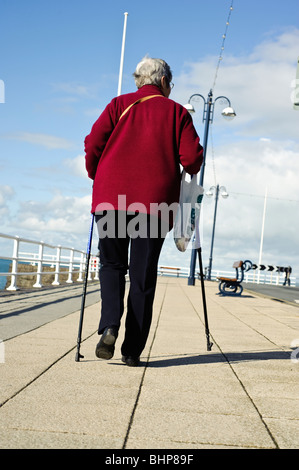 Elderly woman walking with the help of two walking sticks, Aberystwyth, Ceredigion, West Wales UK Stock Photo