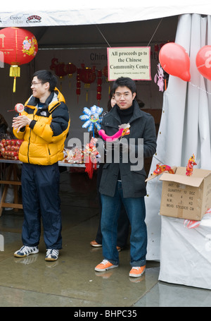 Chinese young men outside a souvenir stall during Chinese New Year celebrations in Trafalgar Square London UK Stock Photo