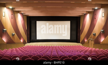 Empty cinema auditorium with line of pink chairs and projection screen. Ready for adding your own picture. Stock Photo