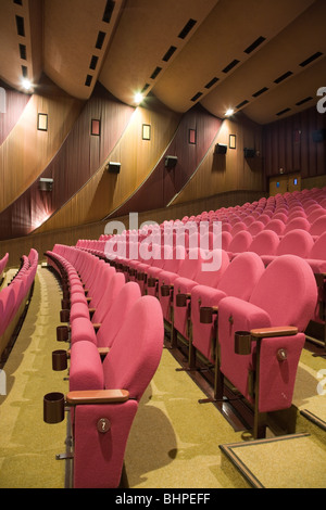Empty cinema auditorium with row #7 of pink chairs. Stock Photo