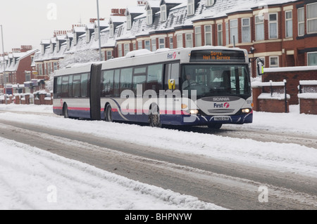 135 Fist bus driving with caution in a bad weather conditions over a slippery road covered with ice and snow in Manchester UK Stock Photo