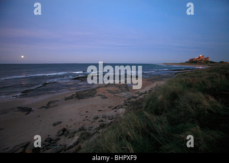 Moon raising over North Sea, beside Bamburgh Castle, on Northumberland coast, England Stock Photo