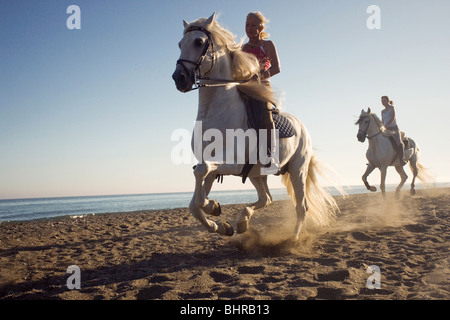 Two women riding horses on beach Stock Photo